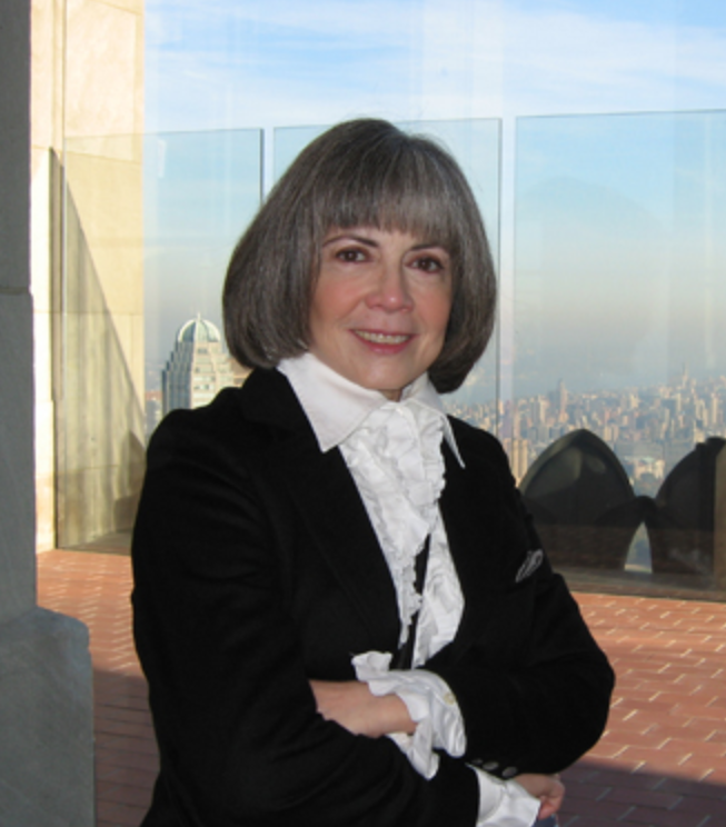 Anne Rice standing in front of city window view