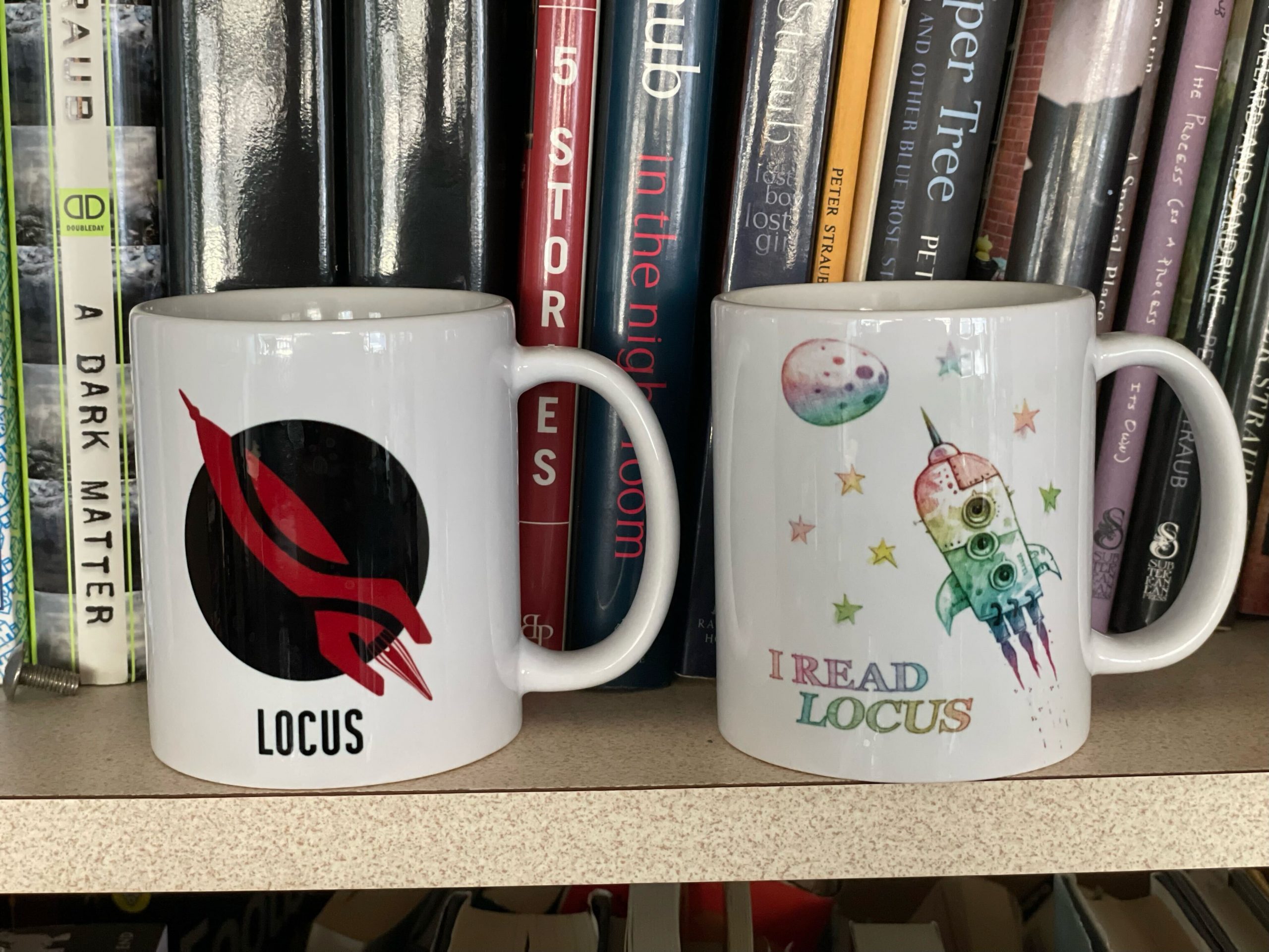 Two coffee mugs, one with a rocket logo and the other with an colorful illustration of a rocket by Shaun Tan