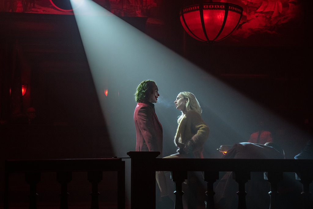 Joker and Harley Quinn in serious conversation in dark hall